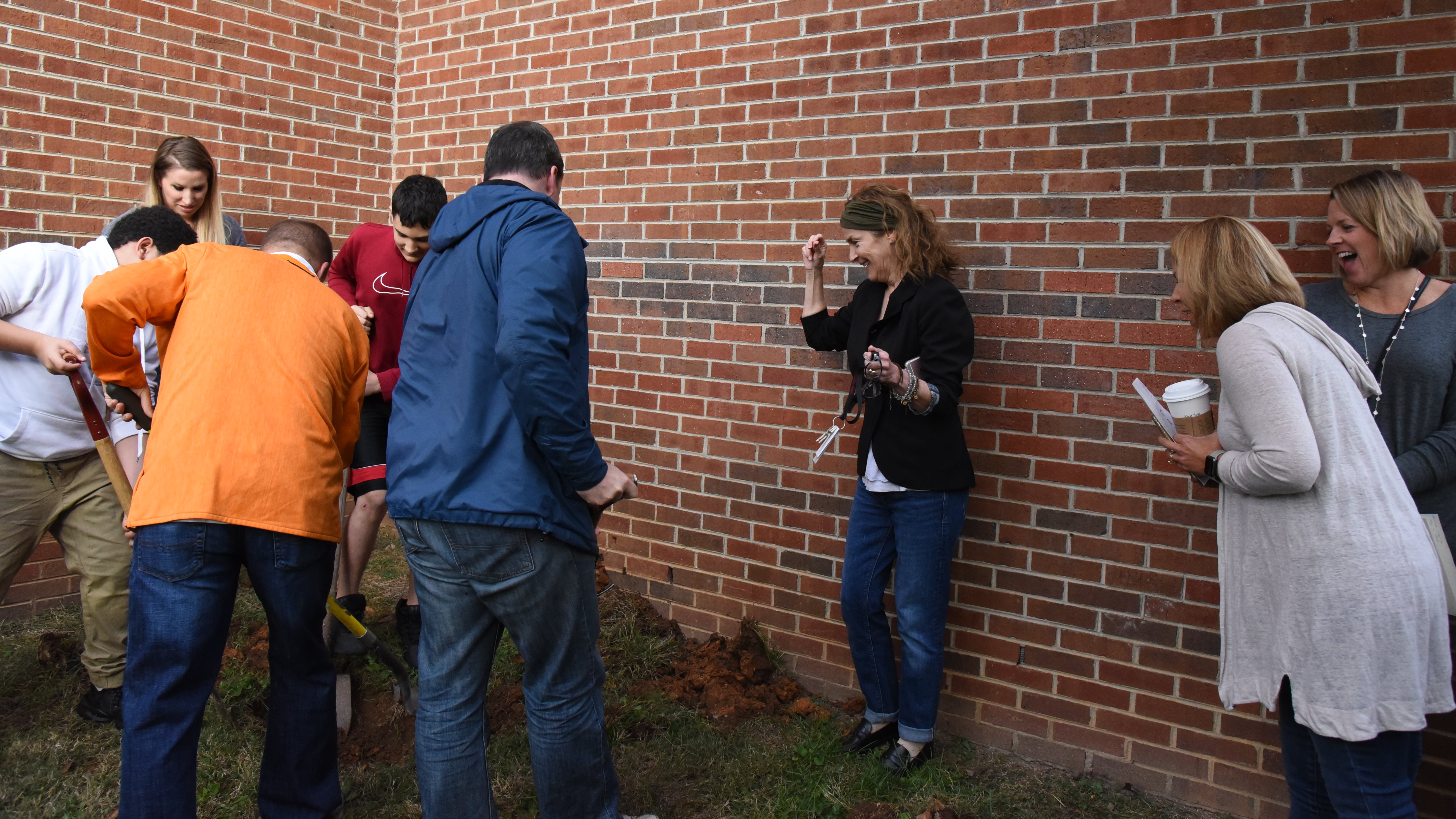 Students and alumni from Gresham Middle School dig up a time capsule as Principal Donna Parker, center, looks on. 